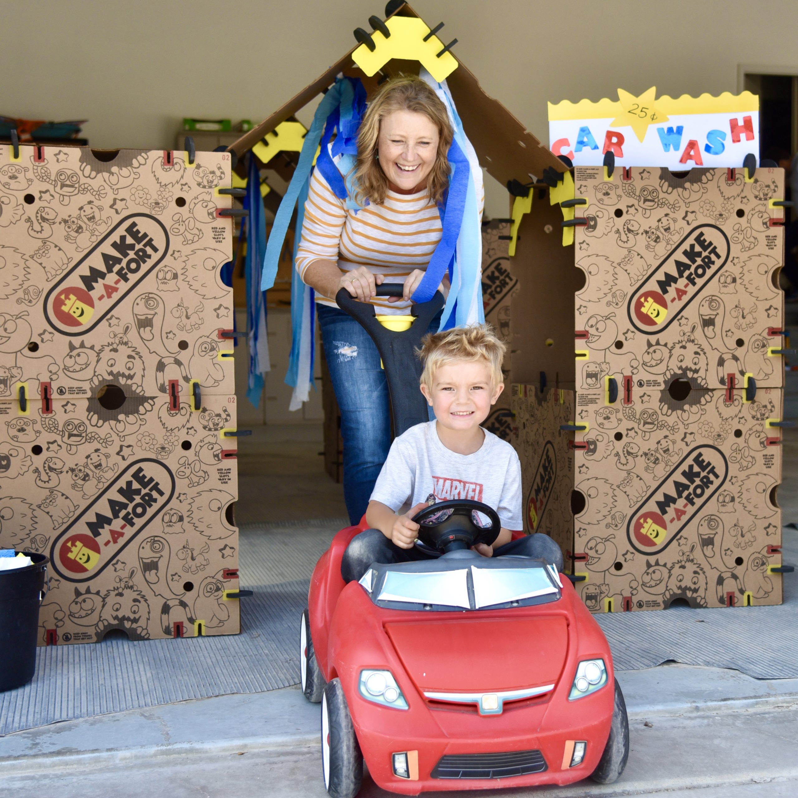 Grand-mère et petit-fils jouant à l'intérieur d'une station de lavage de voitures en carton.